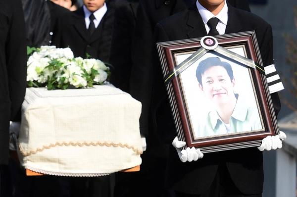 Lee Sun-kyun's son holds a portrait of the late actor at funeral on December 29, 2023.